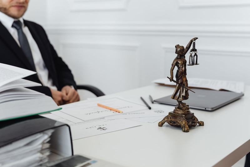 Mesa de trabalho com pastas e uma estatueta da justiça