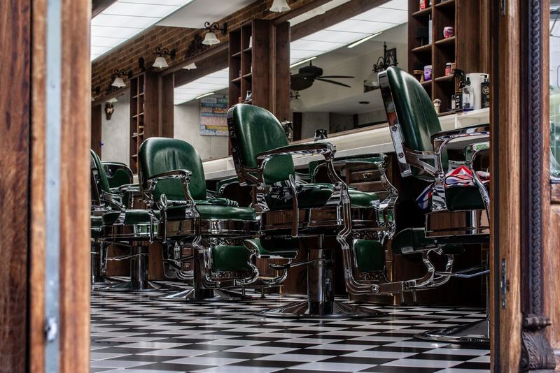 Barbearia clássica com cadeiras de couro verdes e piso xadrez