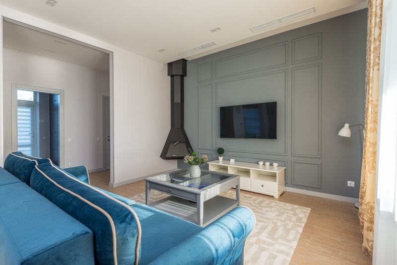 Sala de estar com sofá azul, mesa de centro e janela, em um apartamento arejado