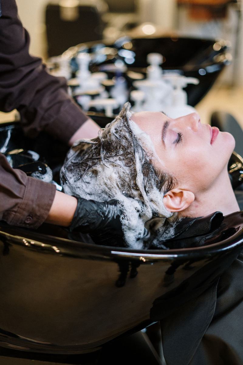 Profissional lavando o cabelo de uma cliente no lavatório